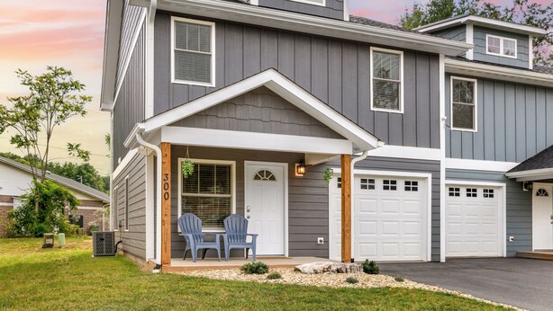 A two-story house with a covered porch, a garage, and a well-maintained lawn.