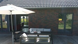 An outdoor patio with a table and chairs, a white umbrella, and a brick wall. - Entdecke die Perfekte Kombination aus Ländlicher Idylle und Urbanem Flair (Kollmar)