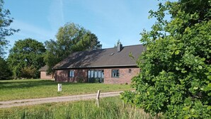 A two-story brick house with a sloped roof, surrounded by a grassy field and trees. - Entdecke die Perfekte Kombination aus Ländlicher Idylle und Urbanem Flair (Kollmar)