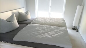 A bedroom with two beds, each with white bedding and grey pillows. - Entdecke die Perfekte Kombination aus Ländlicher Idylle und Urbanem Flair (Kollmar)