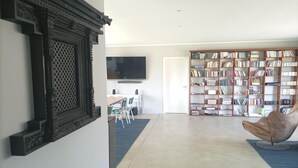 A spacious living room with a large bookshelf, a television, and a comfortable chair. - Entdecke die Perfekte Kombination aus Ländlicher Idylle und Urbanem Flair (Kollmar)