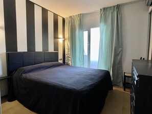 Una habitación de hotel con cama, escritorio y ventana con cortinas.