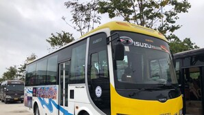 Un autobus Isuzu jaune et blanc avec l’inscription « ISUZU WELCOME » à l’avant.