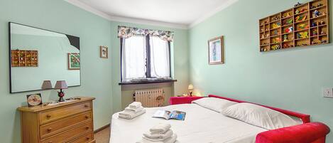 Un dormitorio con cama, cómoda y estante con juguetes.