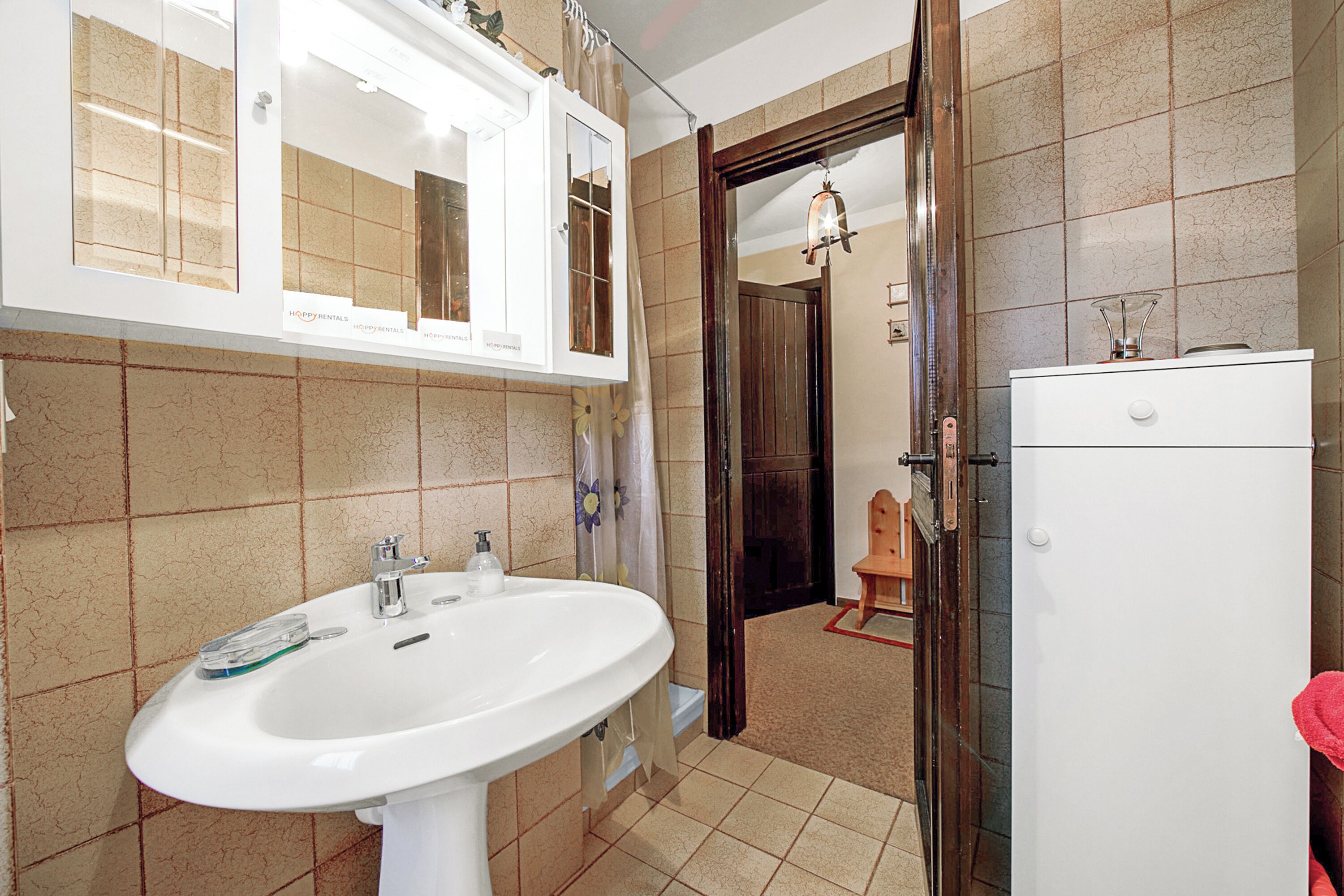 A bathroom with a white sink, a mirror, and a shower area.
