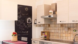 A modern kitchen with a chalkboard wall, a sink, and a dining area with a table and chair. - Panariello a Portamedina (Napoli)
