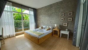 Een slaapkamer met een groot bed, een nachtkastje en een raam met gordijnen.
