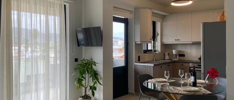 Una cocina moderna con comedor, un televisor montado en la pared y una planta en maceta.