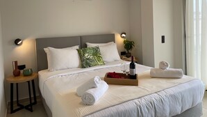 A hotel room with a bed, bedside tables, an air conditioner, a potted plant, and a window with curtains. - MOSSA CITY APARTMENTS (Chania)