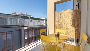 A balcony with yellow chairs and a table, a bamboo screen, and a view of neighboring buildings. - Esperia Home penthouse in Bari with private terrace, Wi-Fi, and air conditioning (Bari)