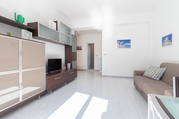 A modern living room with a sofa, TV, and cabinets.