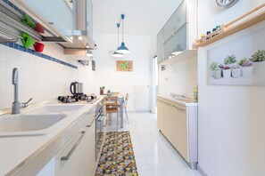 A modern kitchen with a central island, a dining area with chairs, and a patterned rug.