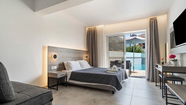 A modern hotel room with a bed, a desk, a chair, and a TV. - Studio 'King Room with Pool View' with Shared Pool, Wi-Fi and Air Conditioning (?e???da?)