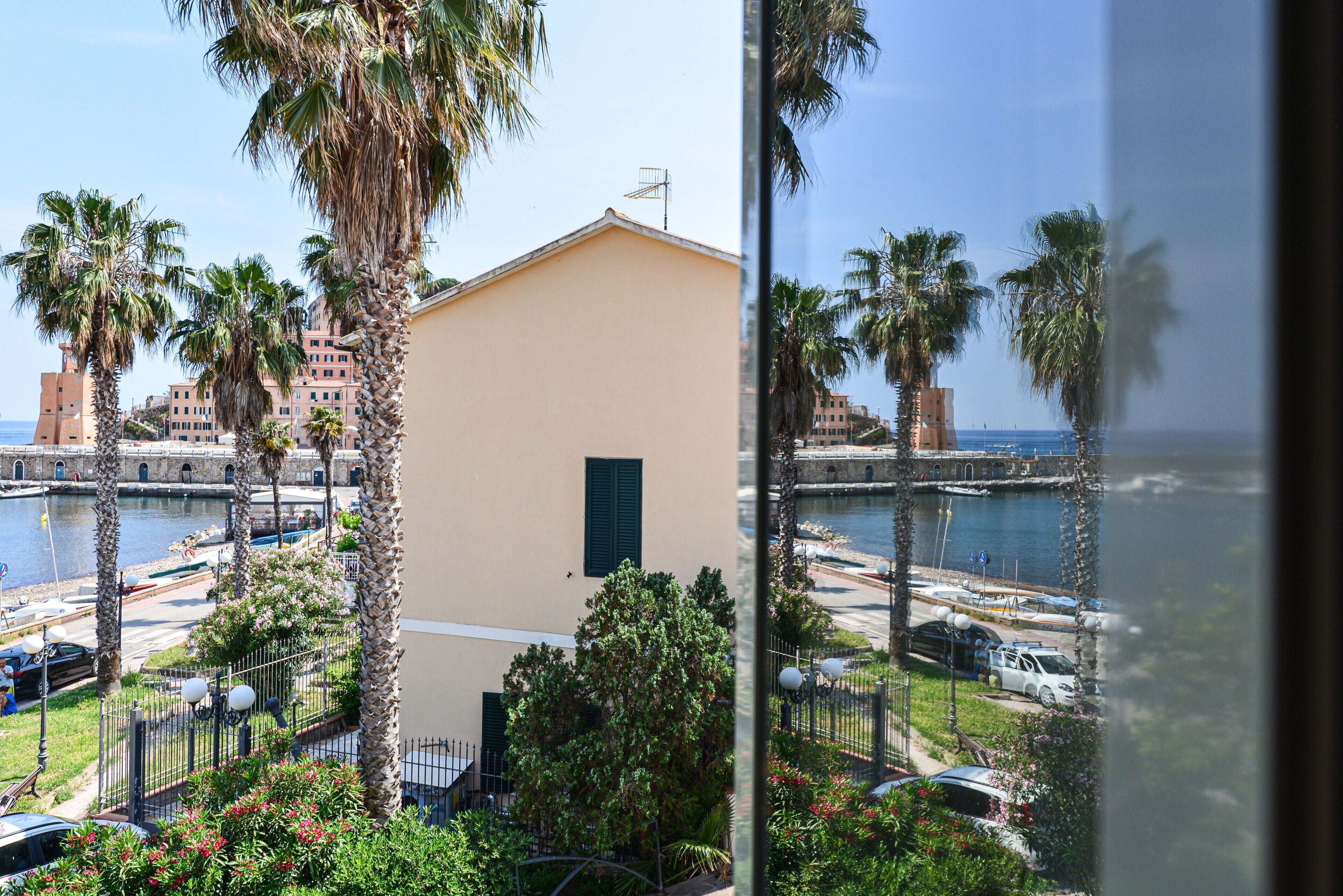 Edificio costiero con balcone, palme e vista sul mare.