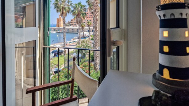 A balcony with a view of a coastal area, including palm trees and buildings.