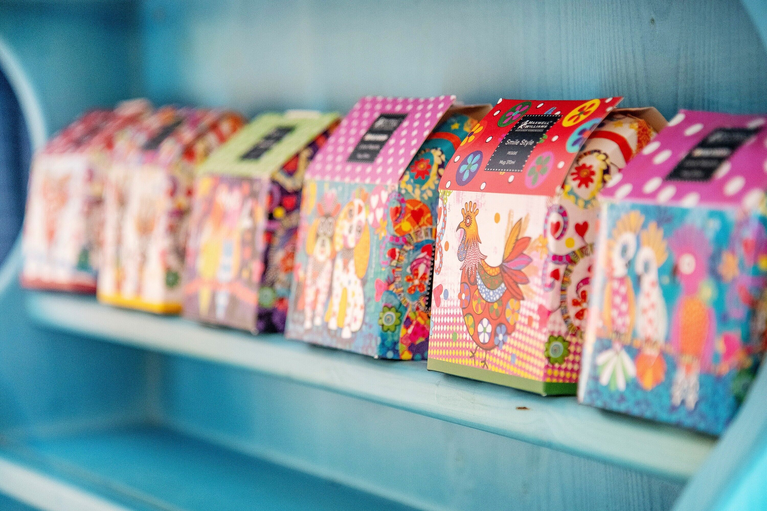 A row of colorful, patterned boxes on a shelf.