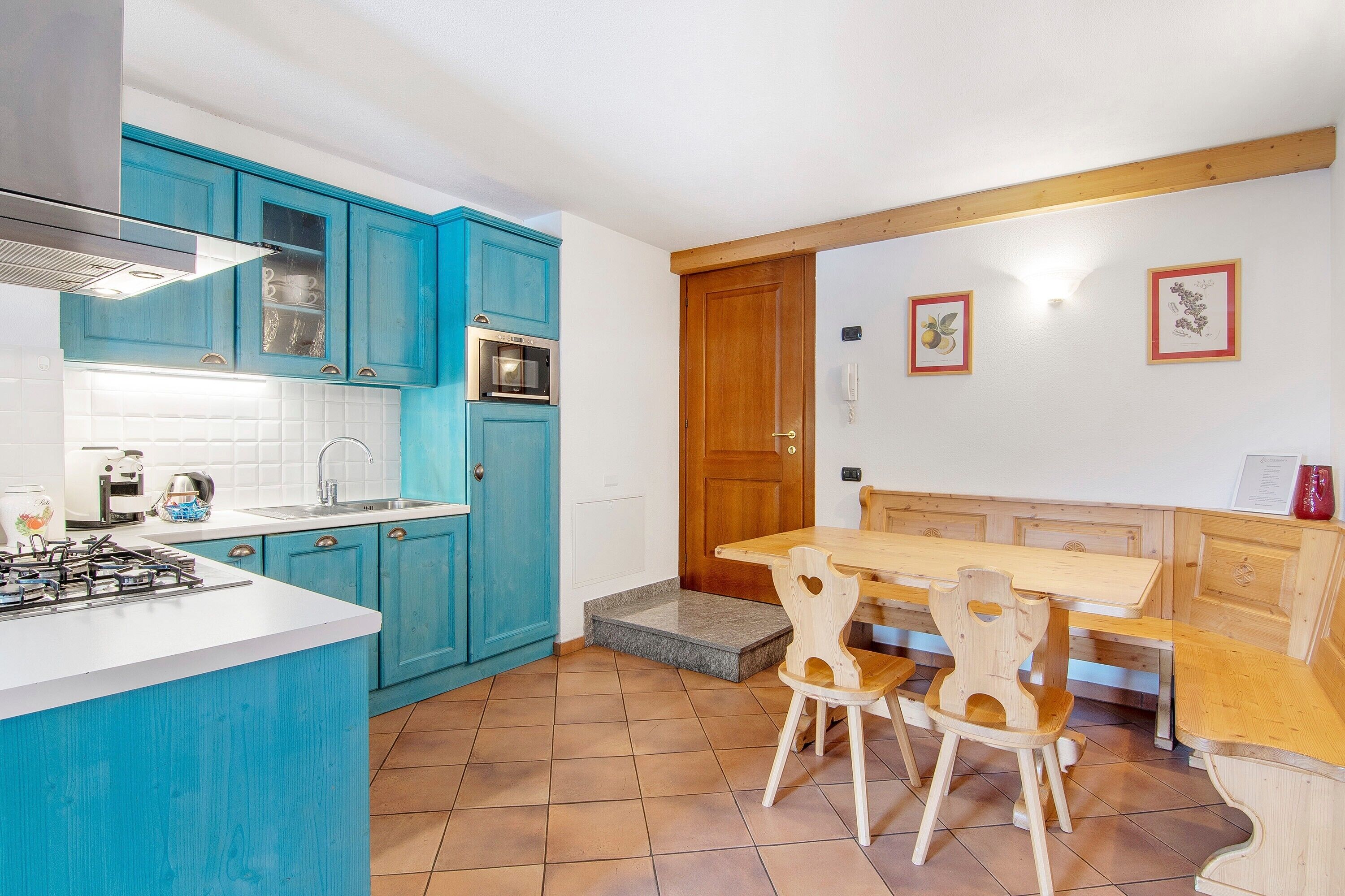 A kitchen with blue cabinets, a wooden dining table, and chairs.