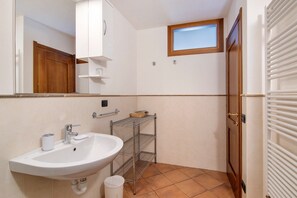 Une salle de bain avec un lavabo, un miroir, des étagères et une fenêtre.