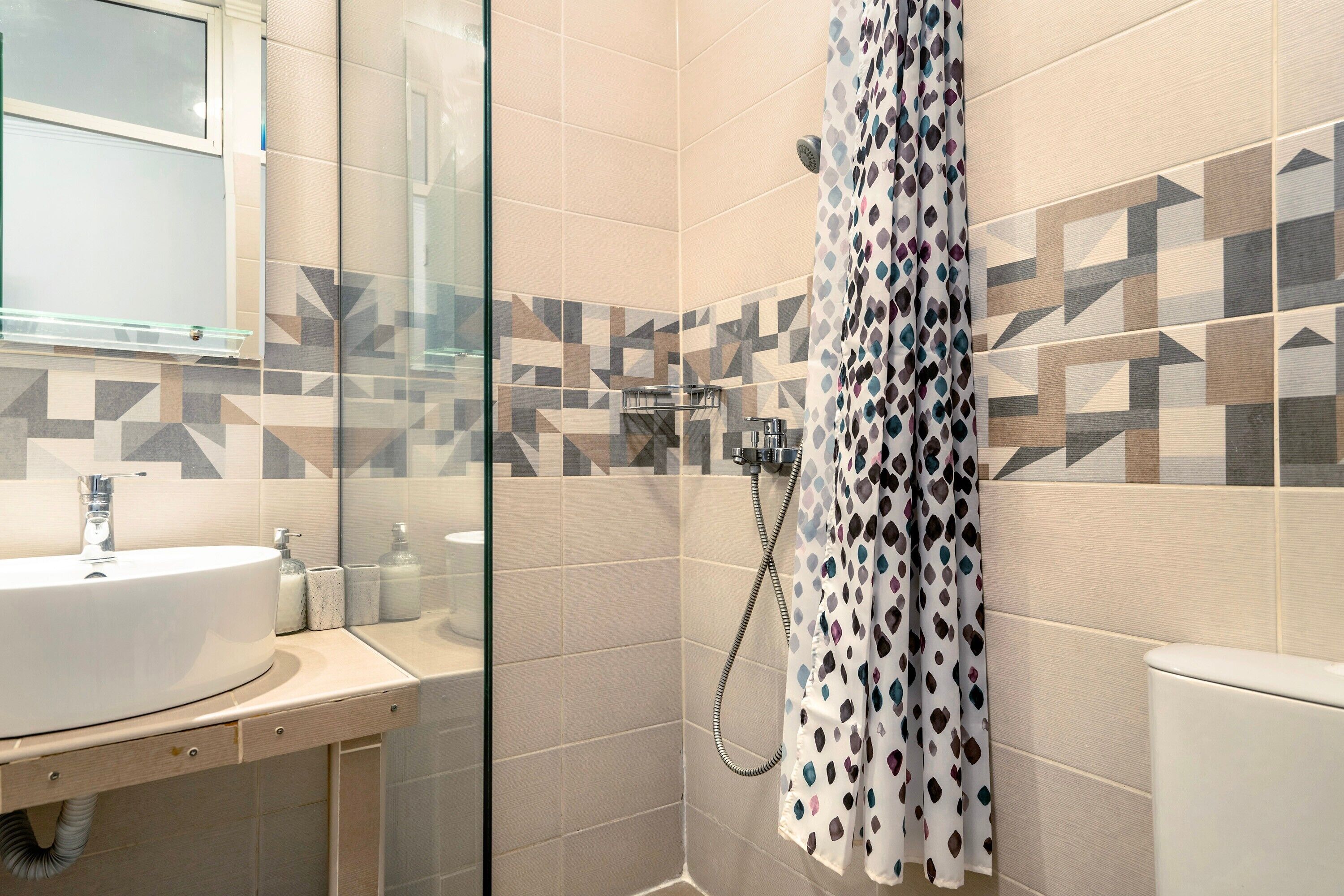 A bathroom with a glass shower enclosure, a sink with a mirror, and a toilet.