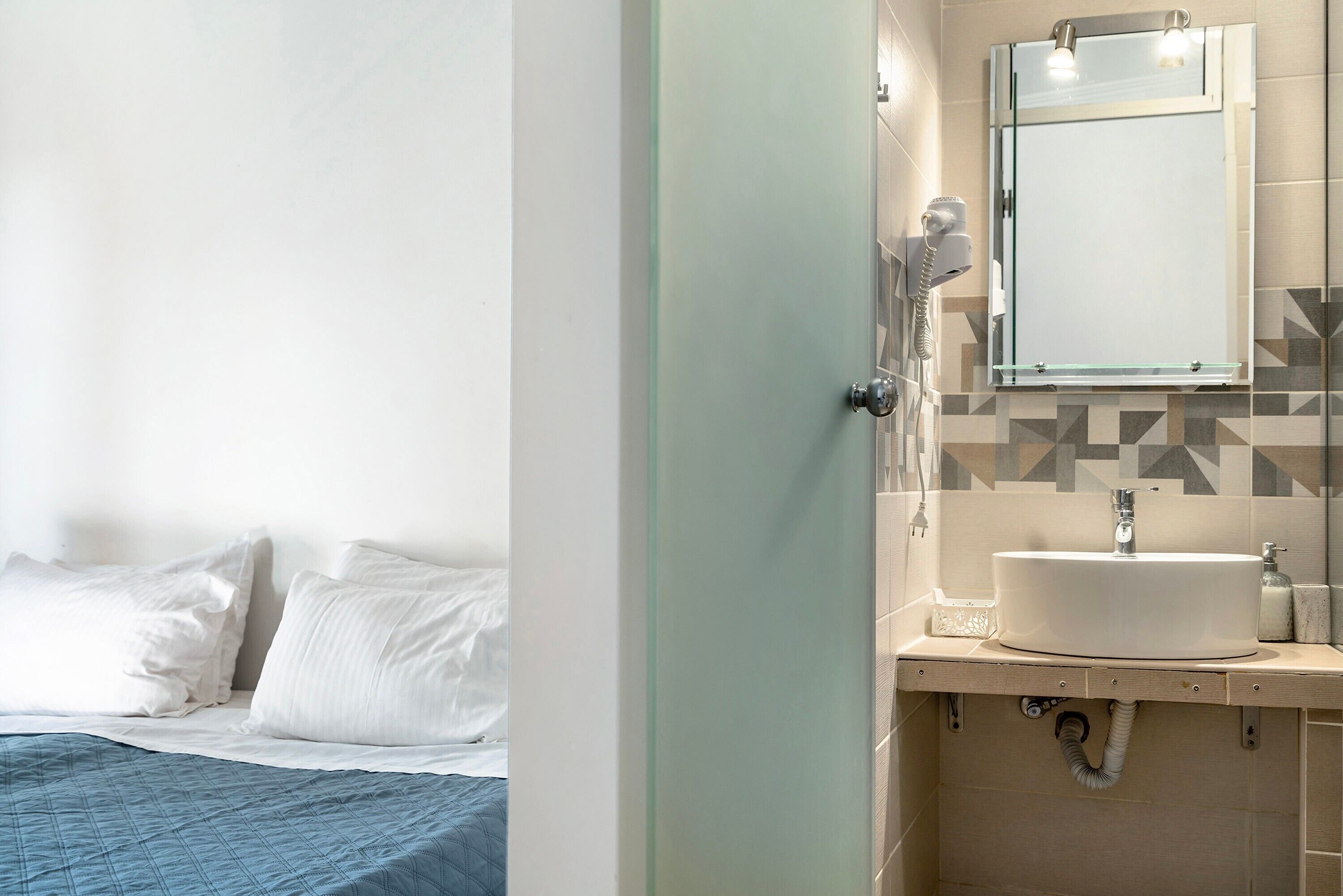 Un baño de hotel con lavamanos, espejo y secador de pelo.