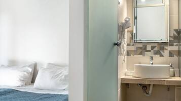 Un baño de hotel con lavamanos, espejo y secador de pelo.
