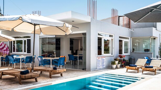 Un espace piscine moderne, doté de chaises longues, de parasols et offrant une vue dégagée sur la piscine.