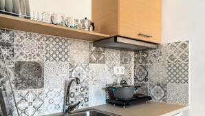 Une cuisine équipée d’un évier en acier inoxydable, d’une cuisinière et de carreaux décoratifs.