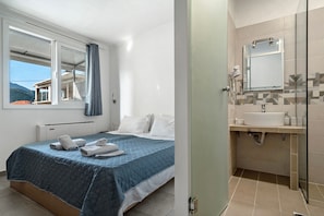 A bedroom with a bed, a window, and a bathroom with a sink and mirror. - Apartment 'Deluxe' with Shared Pool, Wi-Fi and Air Conditioning (?e???da?)