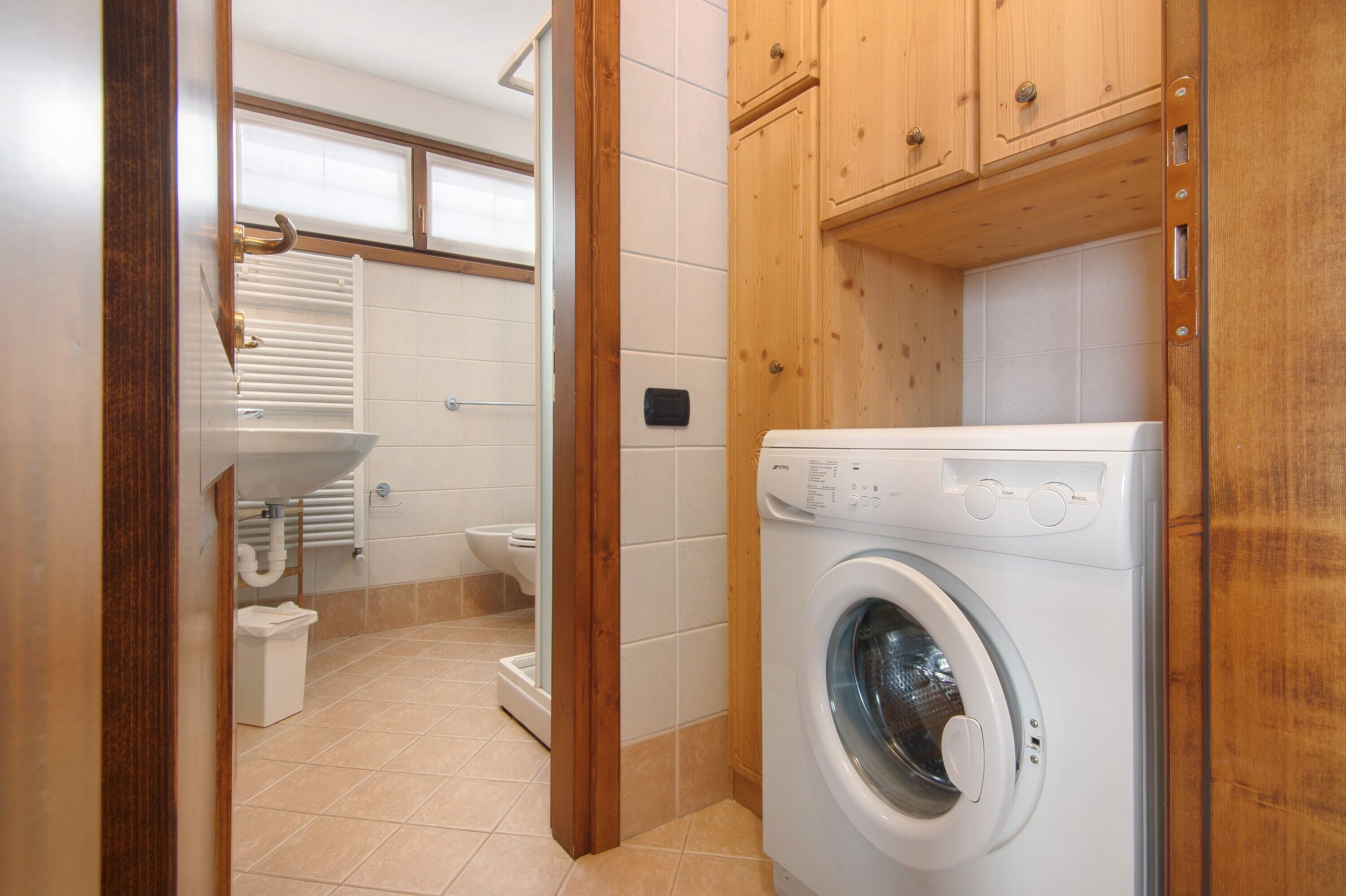 Een wasserette met een wasmachine, een wasbak en een toilet.