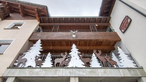 Un bâtiment doté d’un balcon en bois et d’une clôture en métal décorative ornée de motifs de rennes et d’arbres.