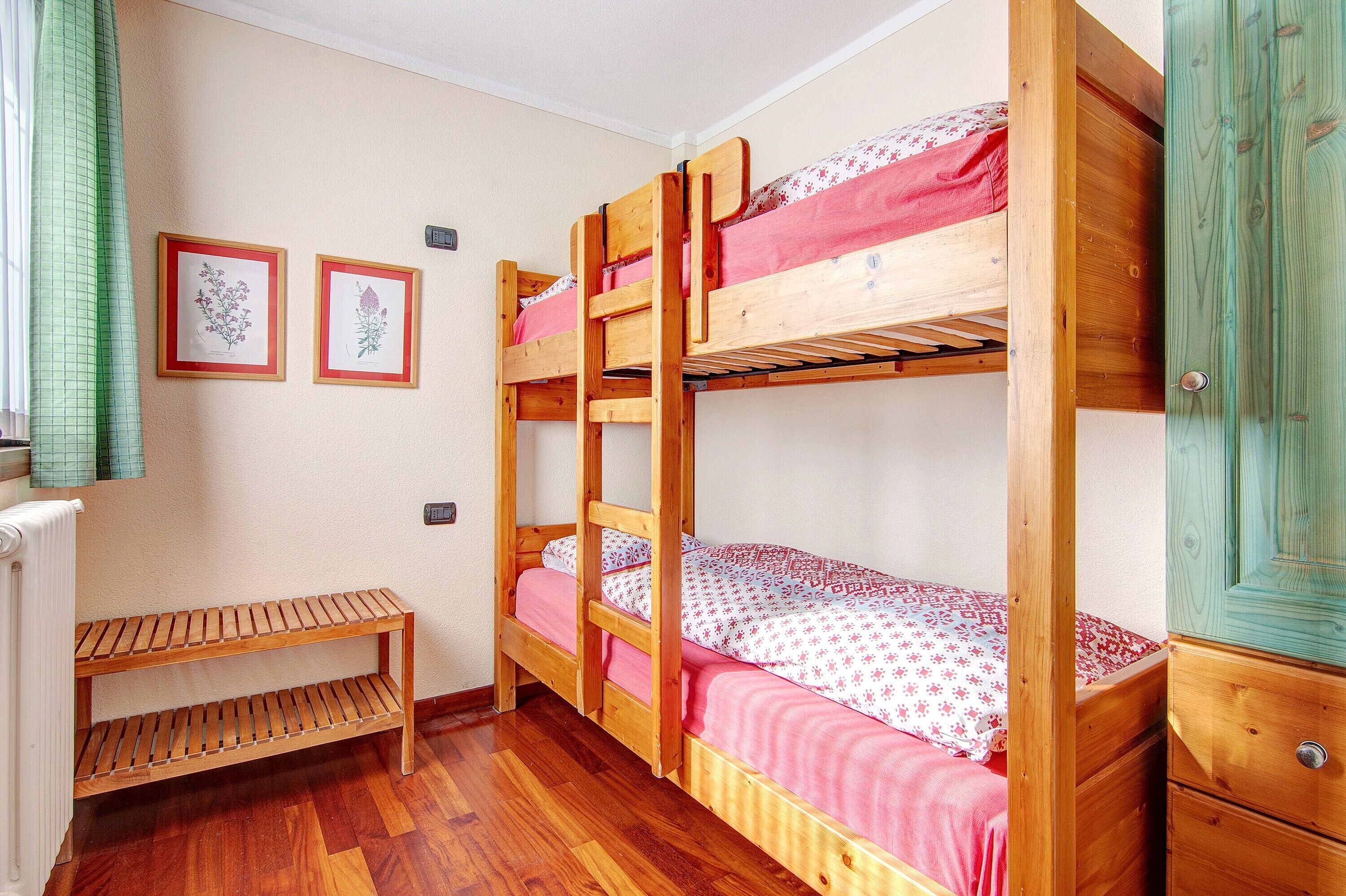 A bunk bed room with a wooden bench and a radiator.