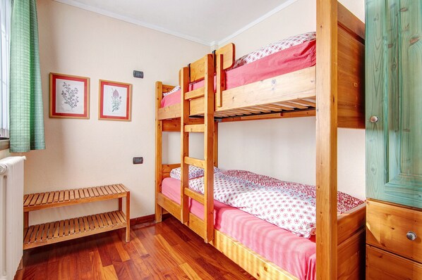 A bunk bed room with a wooden bench and a radiator.