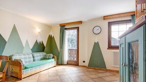 Une pièce comprenant un canapé, une chaise en bois, une horloge et une fenêtre donnant sur une montagne.