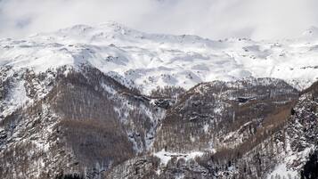 A mountainous landscape with snow-covered peaks and forested valleys.