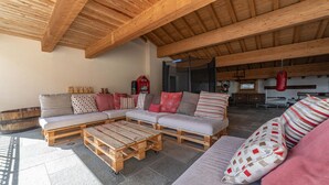 Un vaste espace de vie doté d’un plafond en bois, d’un grand canapé d’angle et d’une table basse.