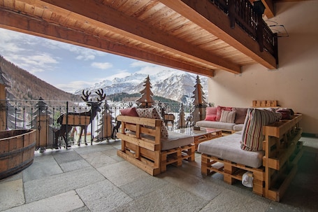 A wooden deck with a sofa and chairs, a wooden bench, and a view of mountains.. Hotel Apartment "Residence Larice Bianco N2" with Shared Terrace & Wi-Fi