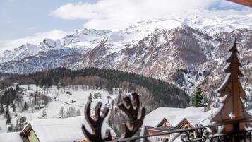 Un paysage de montagne avec des sommets enneigés et un village en contrebas.