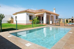 Ein Haus mit Swimmingpool, umzäunter Garten und blauem Himmel.