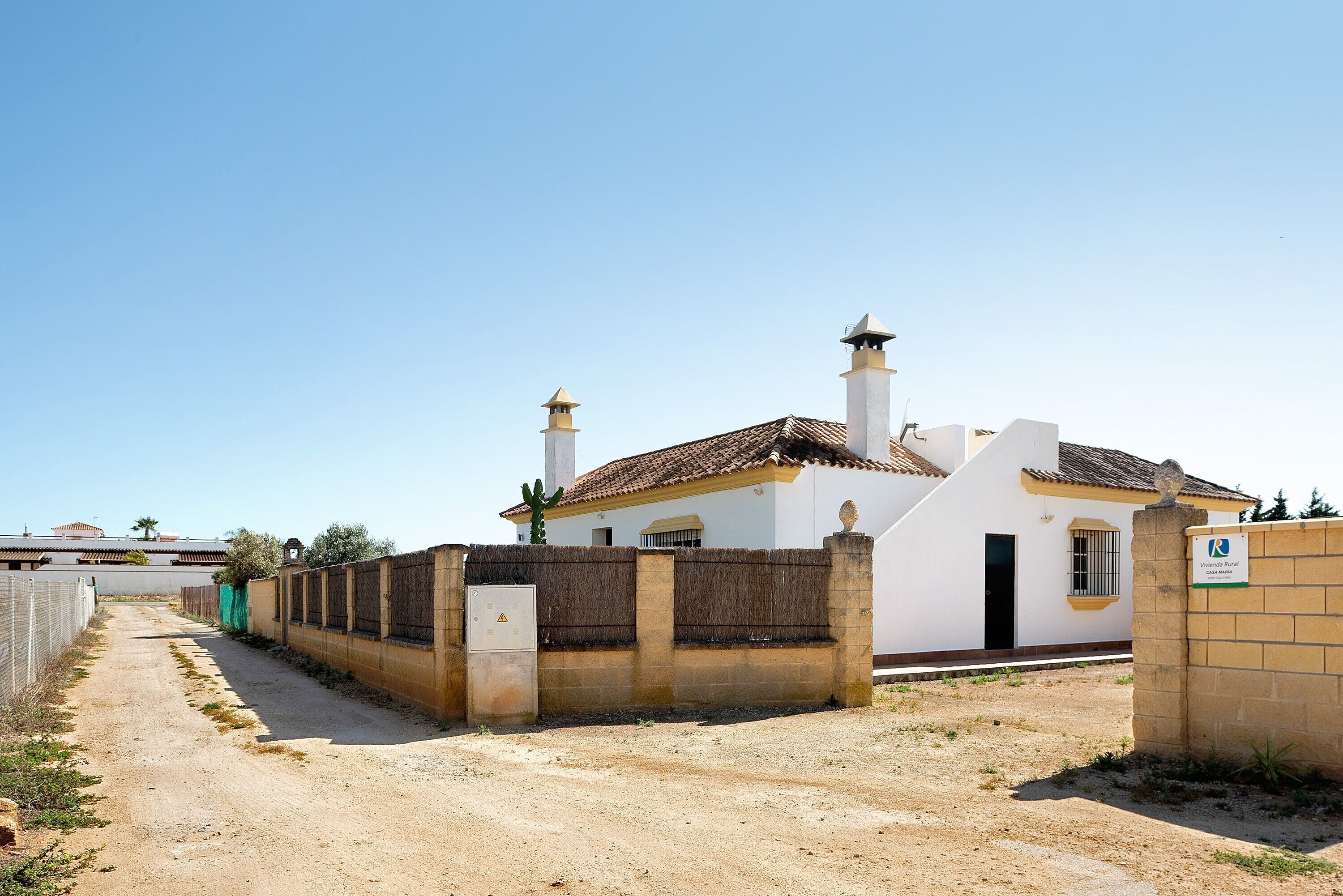 A building with a white facade, two chimneys, and a gated entrance.