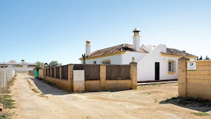Um edifício com fachada branca, duas chaminés e um portão.