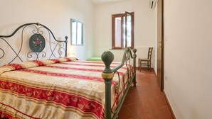 Ein Schlafzimmer mit einem Bett, einem Fenster, einem Sessel und einer Tür.