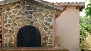 Ein Steinhaus mit Bogenportal, einer kleinen Außenbestuhlung und einer Steinmauer.