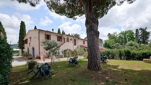 Eine Villa mit Garten, Sitzgelegenheit im Freien und einem großen Baum.