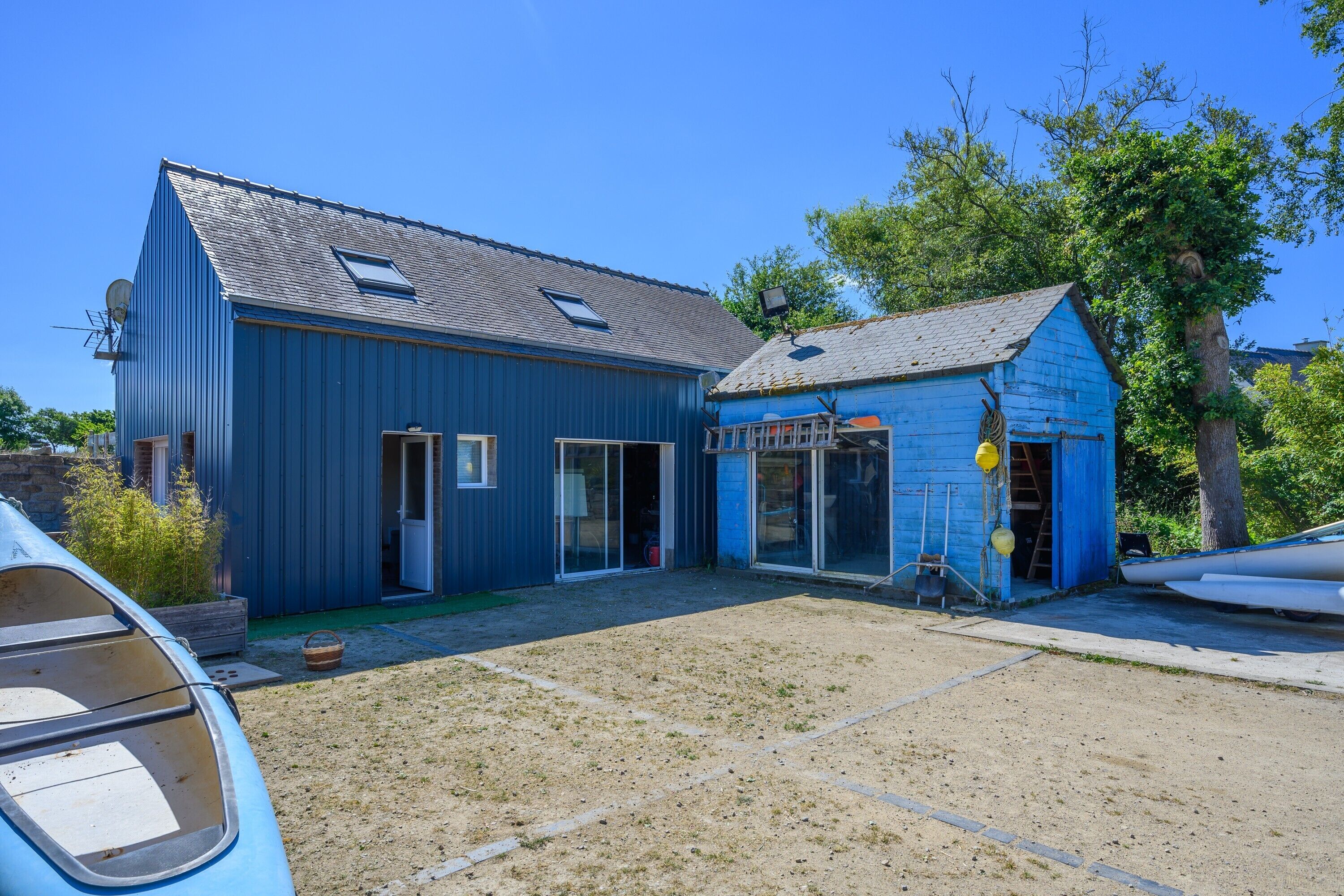 A blue building with a garage, a covered outdoor area, and a boat.