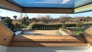 A modern interior with a skylight, a view of a landscaped garden, and a wooden ceiling. - Petit duplex proche mer (Plouhinec)