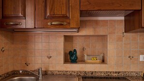 Eine Küche mit Holzschränken, einer Edelstahl-Spüle, einem eingebauten Herd und einer Spritzschutzwand mit quadratischen Fliesen.