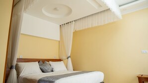 Un dormitorio con cama, cortinas y una lámpara en el techo.