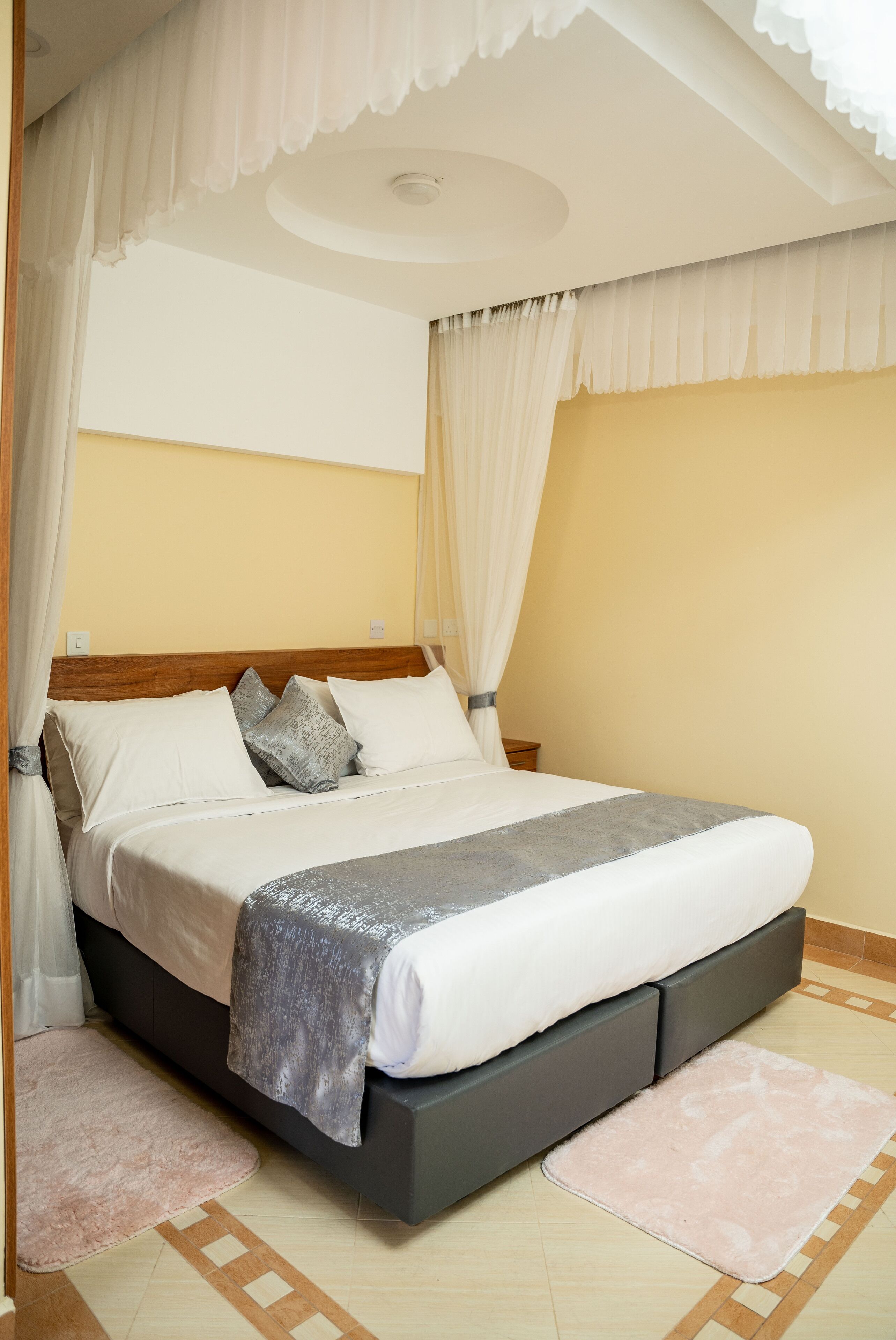 A neatly made bed with a grey headboard, white bedding, and a grey throw blanket.