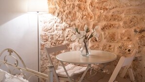 Ein runder Tisch mit Blumen in einer Vase, einer Lampe und einer Steinwand.