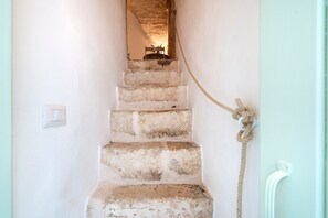 A staircase with a rope tied to the wall, a light switch, and a power outlet.